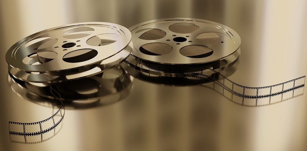 Artwork of a traditional cinema film reel on a gold-coloured background.