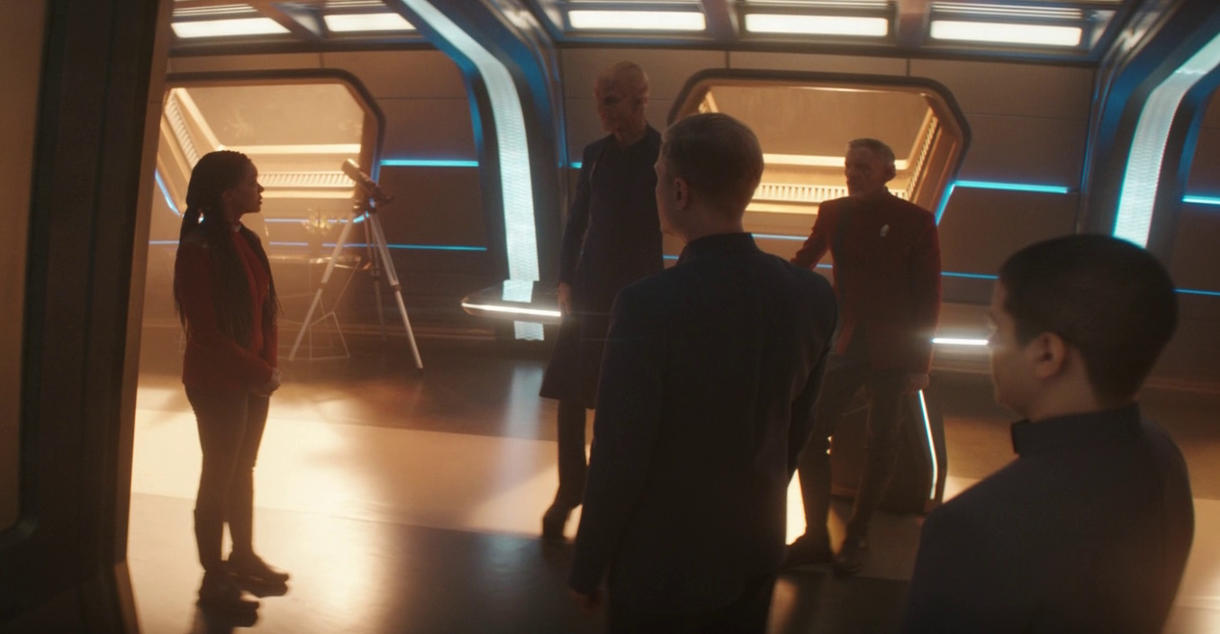 Still frame from Star Trek: Discovery Season 5 (2024) showing Burnham, Saru, Stamets, Rayner, and Adira in the ready-room.