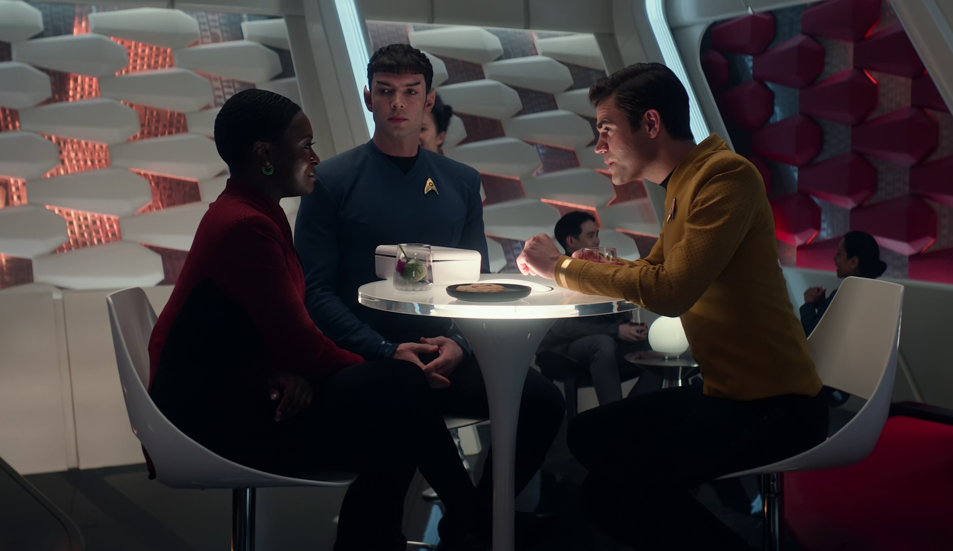 Still frame from Star Trek: Strange New Worlds Season 2 (2023) showing Uhura, Spock, and Kirk at a table.