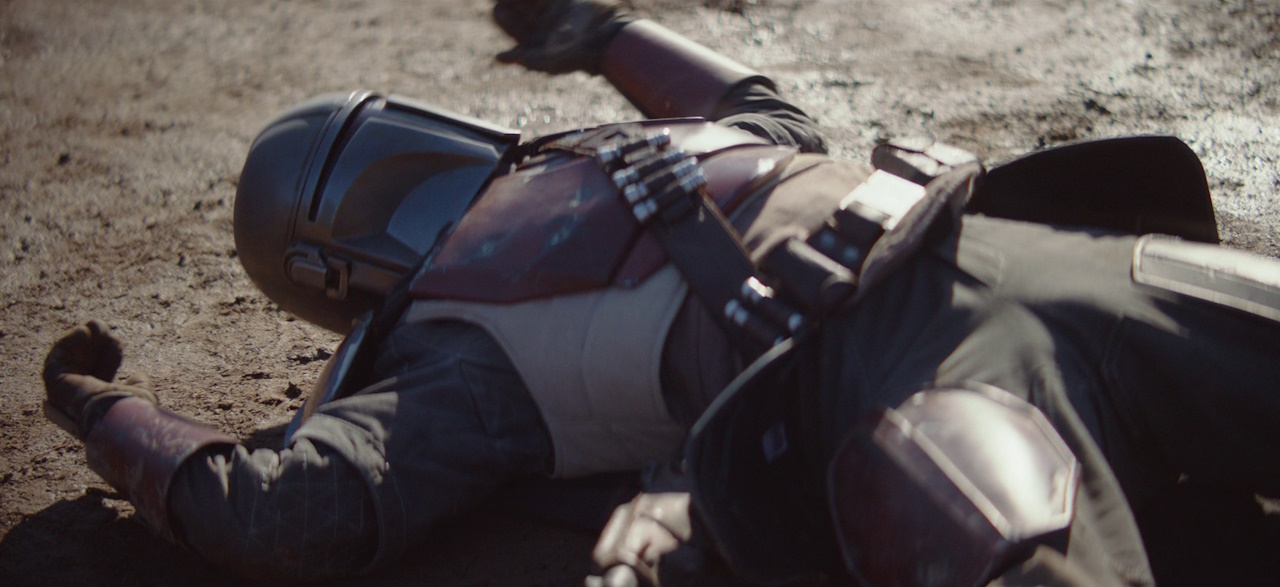 Still frame from The Mandalorian Season 1 (2019) showing the title character knocked down on the ground.