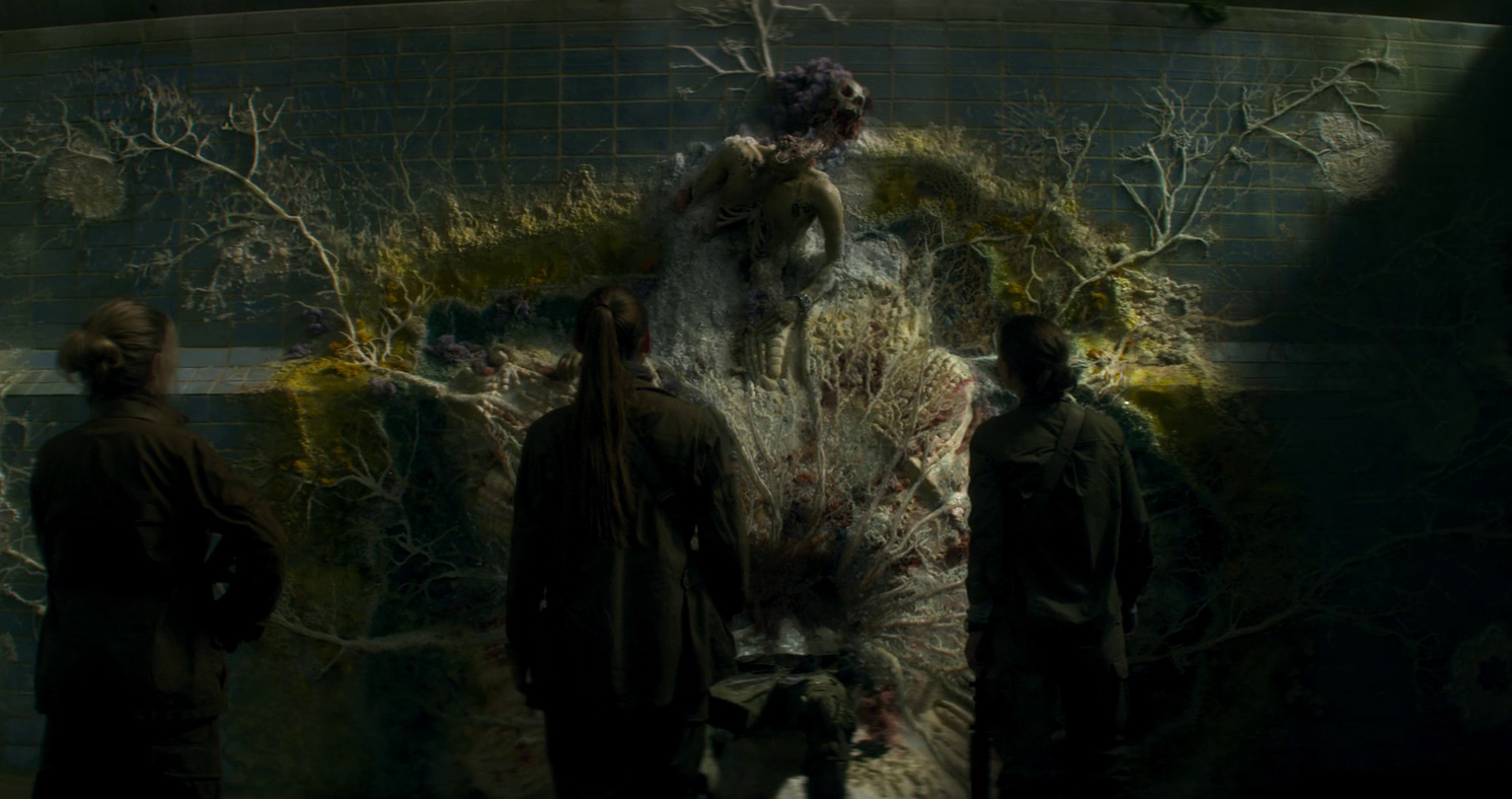 Still frame from Annihilation (2018) showing characters examining a mutated corpse.