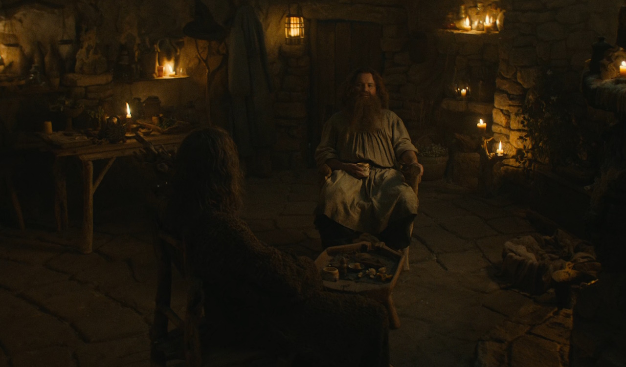 Still frame from The Lord of the Rings: The Rings of Power Season 2 (2024) showing Gandalf and Tom Bombadil in Tom's cottage.