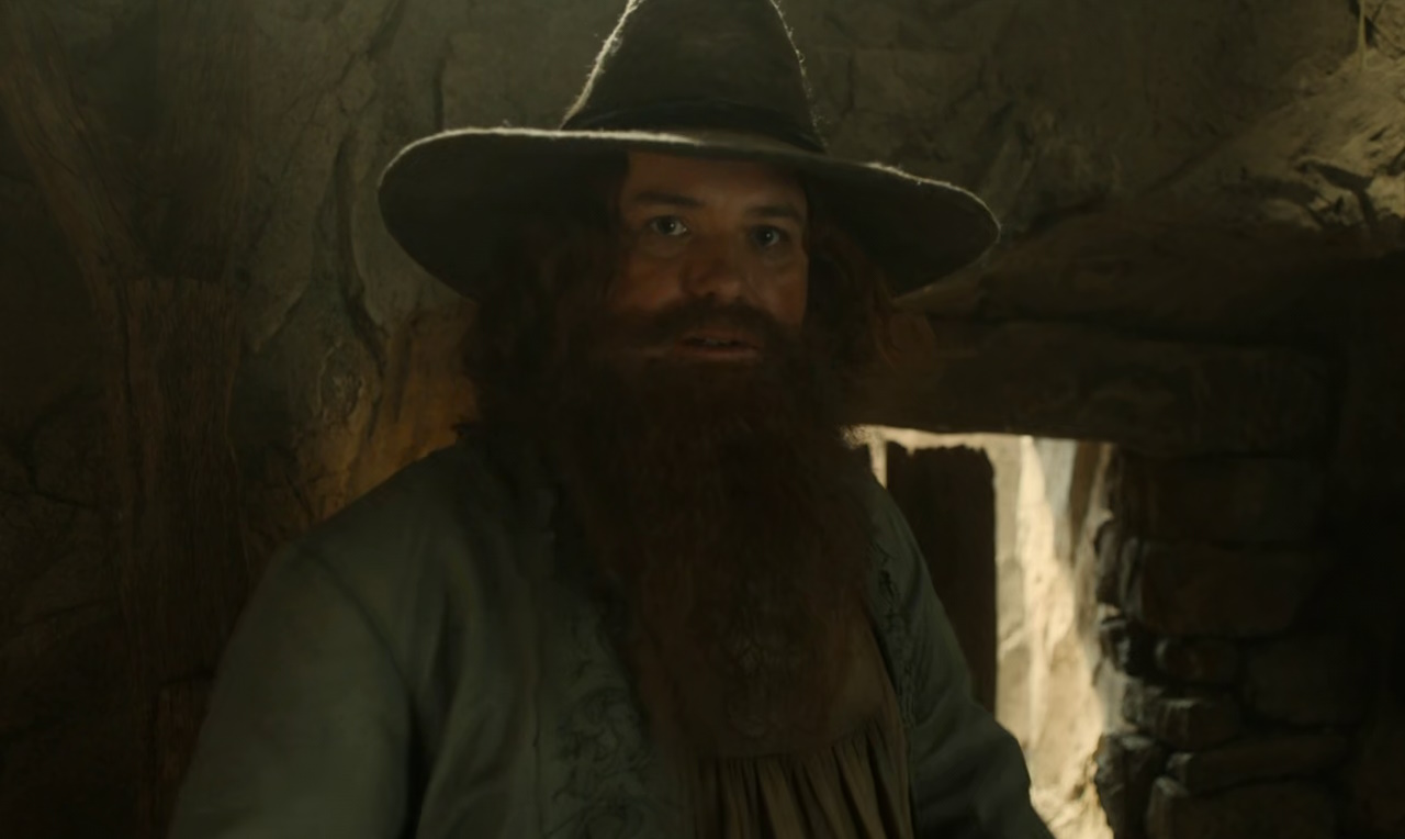Still frame from The Lord of the Rings: The Rings of Power Season 2 (2024) showing Tom Bombadil with his coat and hat on.