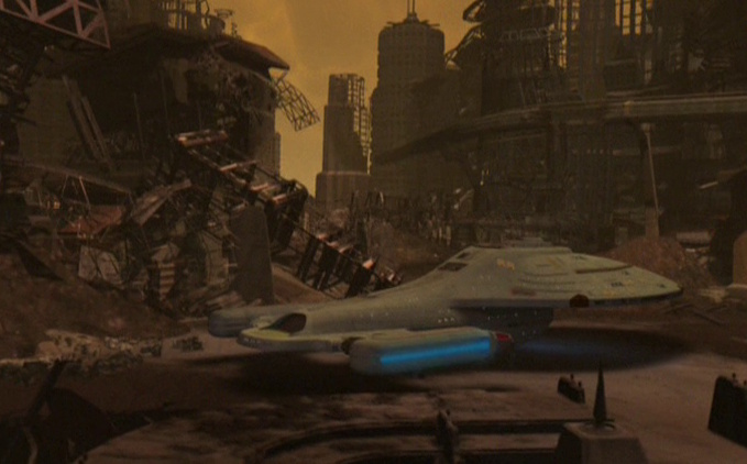 Still frame from Star Trek: Voyager showing the USS Voyager on the surface of a planet, surrounded by ruins.