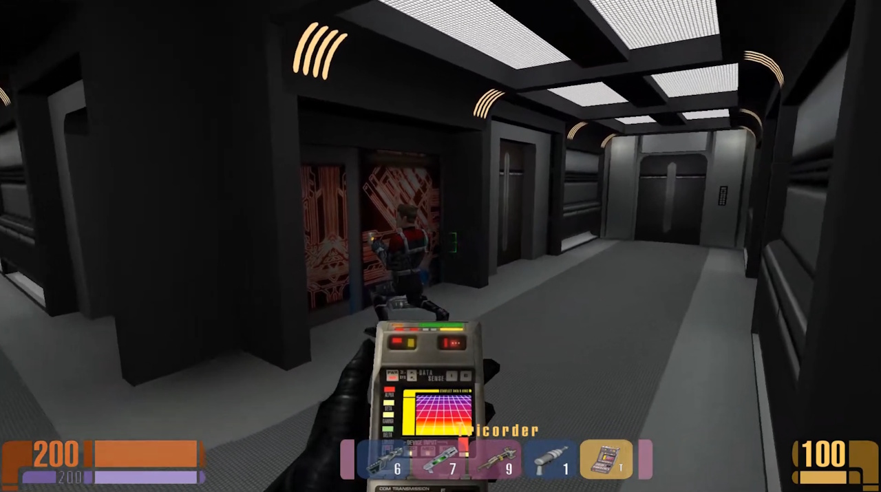 Screenshot of Star Trek: Voyager - Elite Force showing a first person viewpoint, a tricorder, and one of the hallways aboard the USS Voyager.