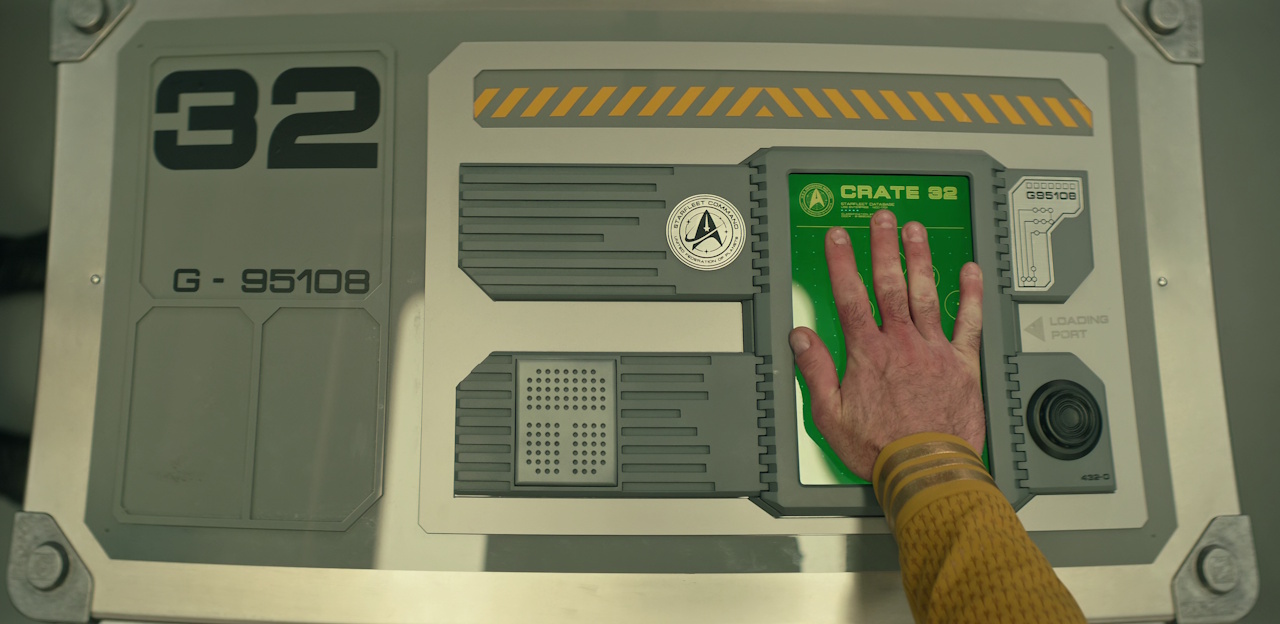Still frame from Star Trek: Strange New Worlds Season 2 Episode 10 (2023) showing Captain Pike's hand activating a sealed crate.