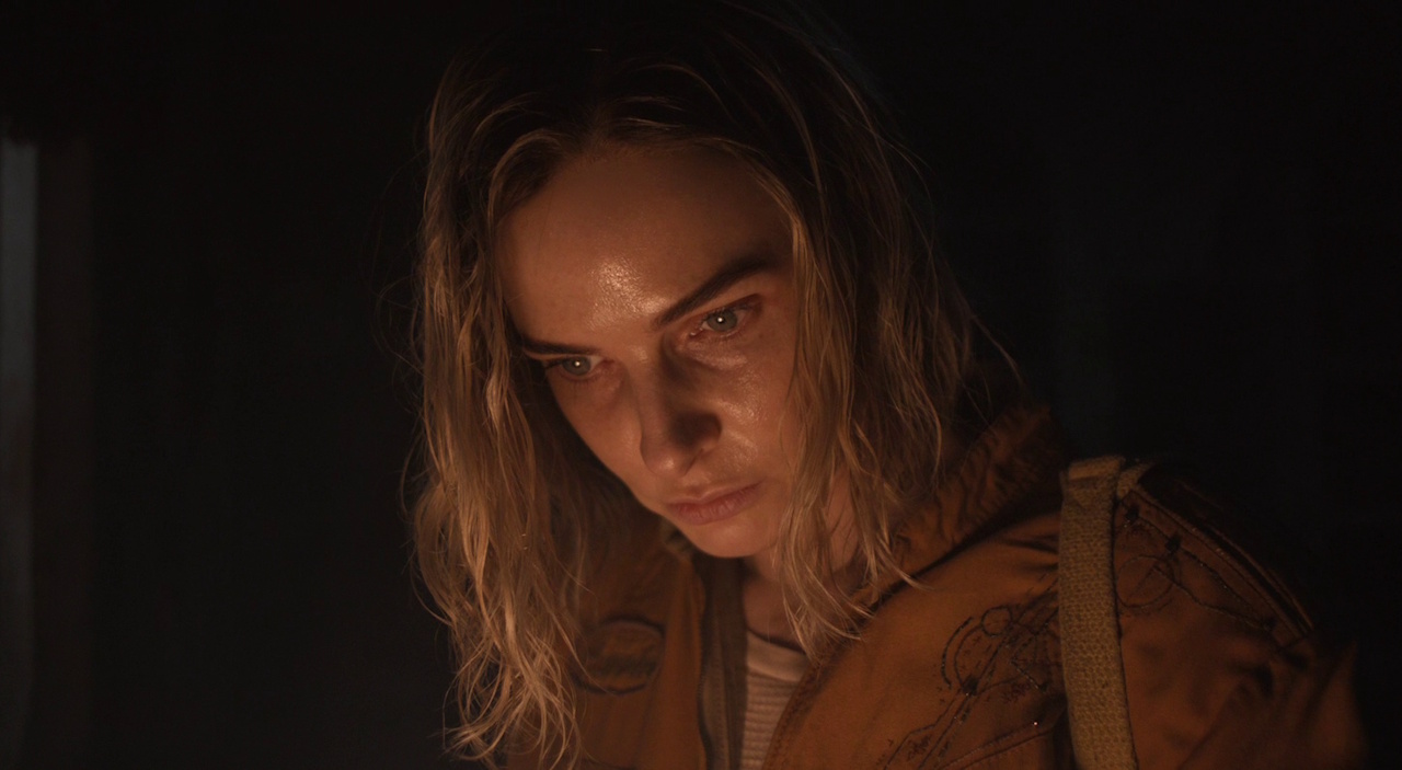 Still frame from Silo Season 2 (2024-25) showing Juliette's face illuminated by a torch.