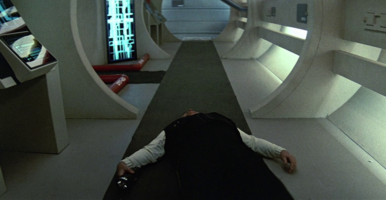 Still frame from Star Trek V: The Final Frontier showing Scotty laying unconsious on the floor.