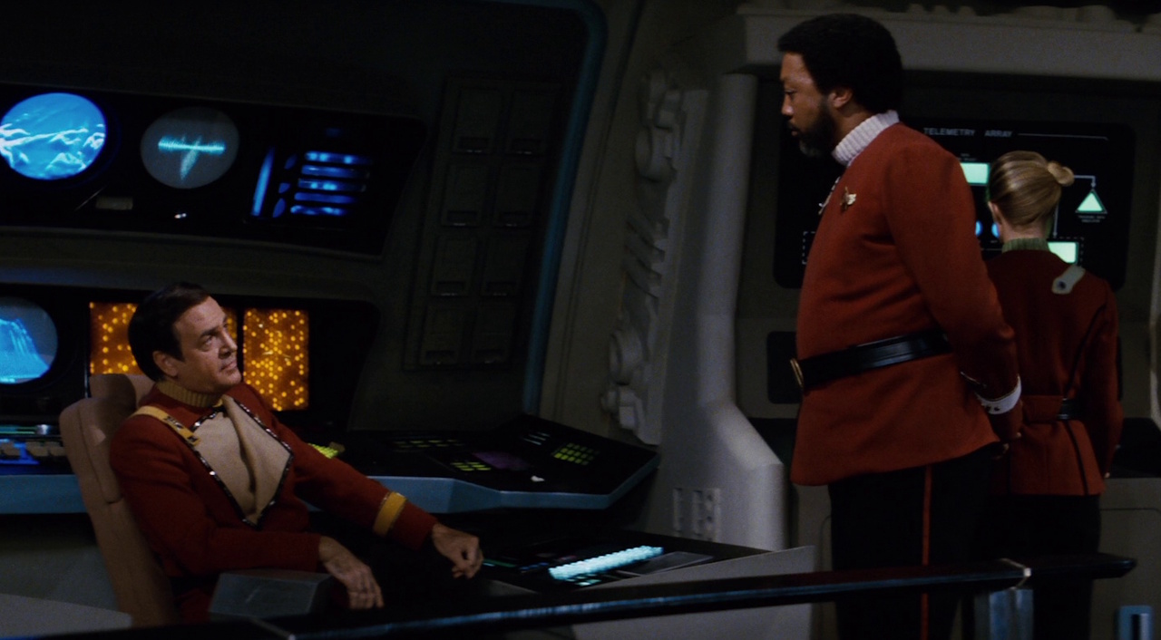 Still frame from Star Trek II: The Wrath of Khan showing two Starfleet officers on the bridge of their ship.