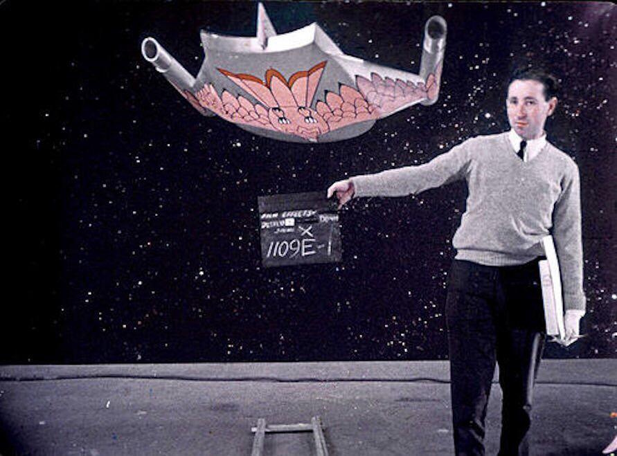 Behind-the-scenes photo from the set of Star Trek: The Original Series showing a crew member with a clapper board and the Romulan Bird-of-Prey filming model.