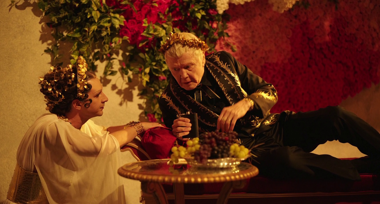 Still frame from Megalopolis (2024) showing two characters in Roman-inspired costumes.