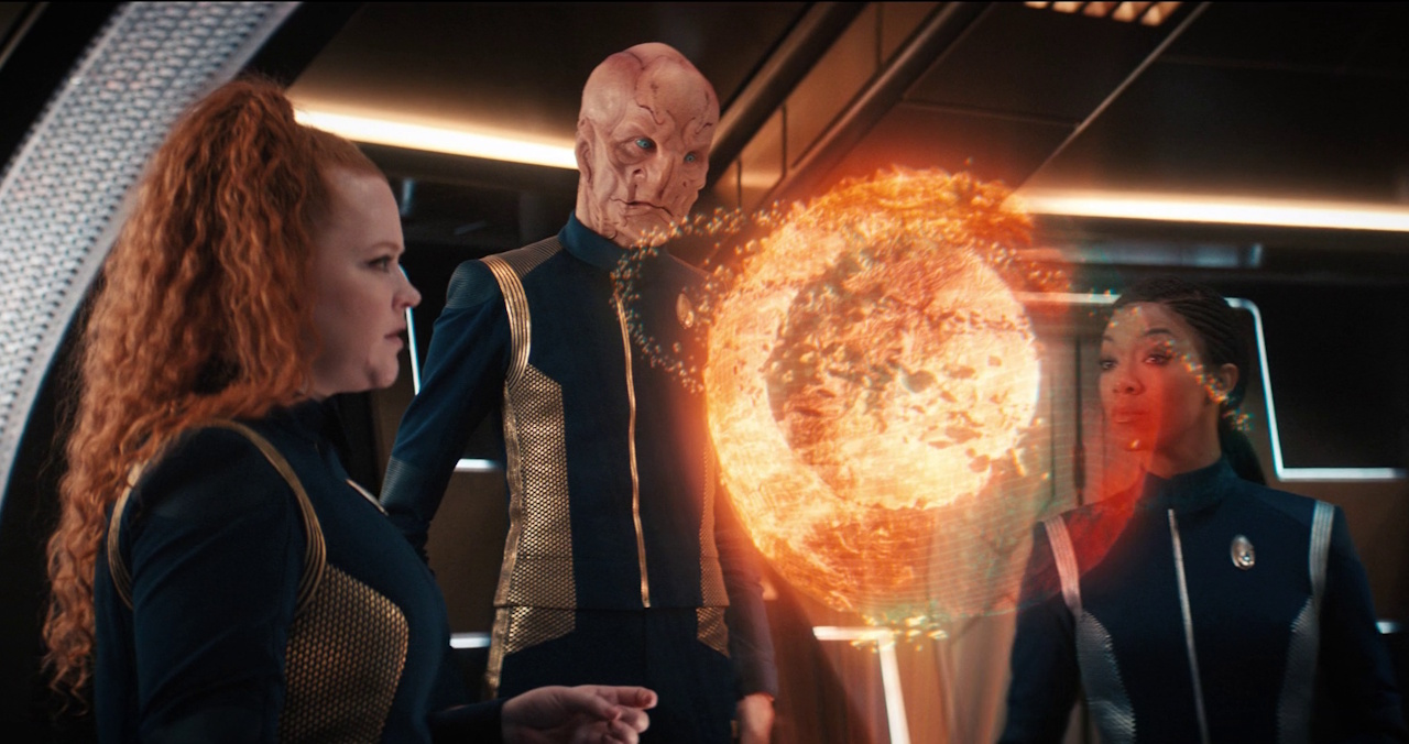 Still frame from Star Trek: Discovery Season 3 showing Tilly, Saru, and Burnham with a hologram of the dilithium planet.