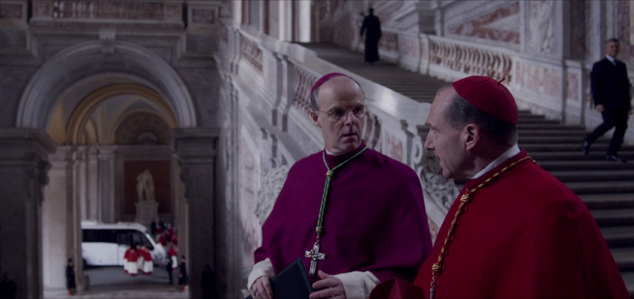 Still frame from Conclave (2024) showing Cardinal Lawrence and Monsignor O'Malley in conversation.