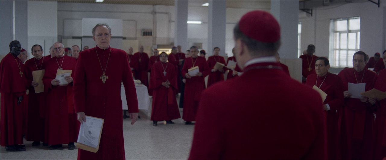 Still frame from Conclave (2024) showing Cardinal Tremblay being confronted by the other cardinals.