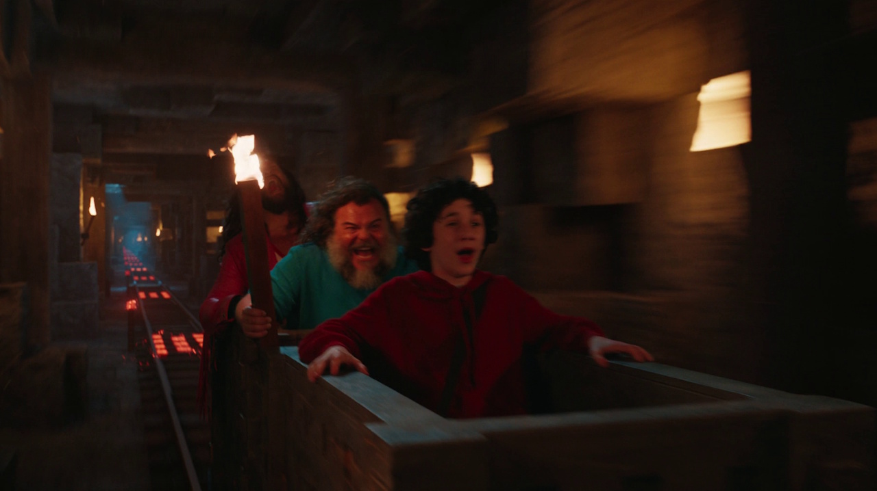 Still frame from A Minecraft Movie showing Henry, Steve, and Garrett in a runaway mine cart.