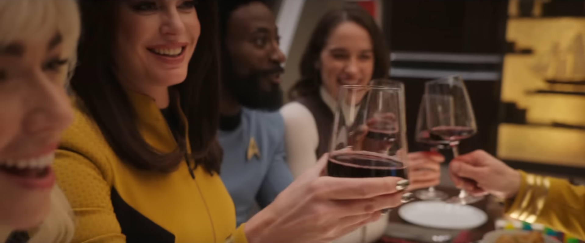 Still frame from the Strange New Worlds Season 3 trailer showing multiple main characters with wine glasses.