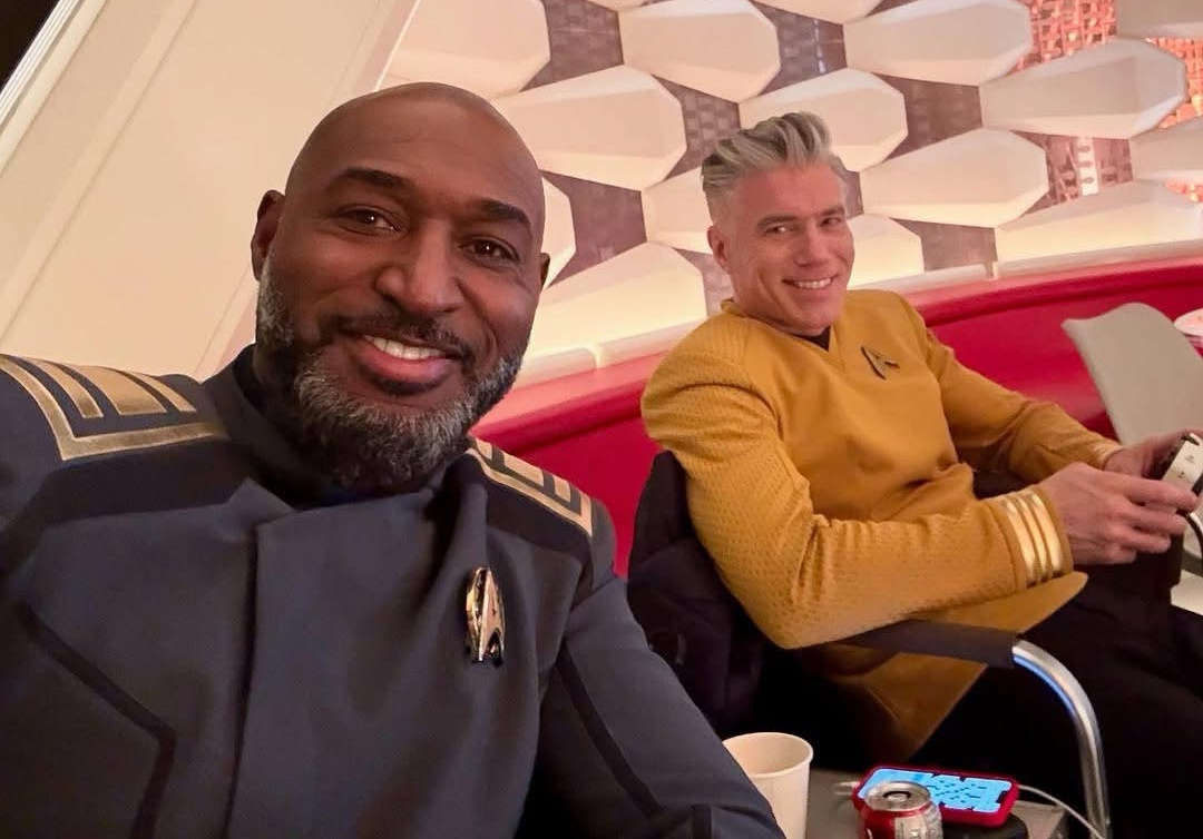 Behind-the-scenes photo from the set of Strange New Worlds Season 4 showing Adrian Holmes and Anson Mount in costume.
