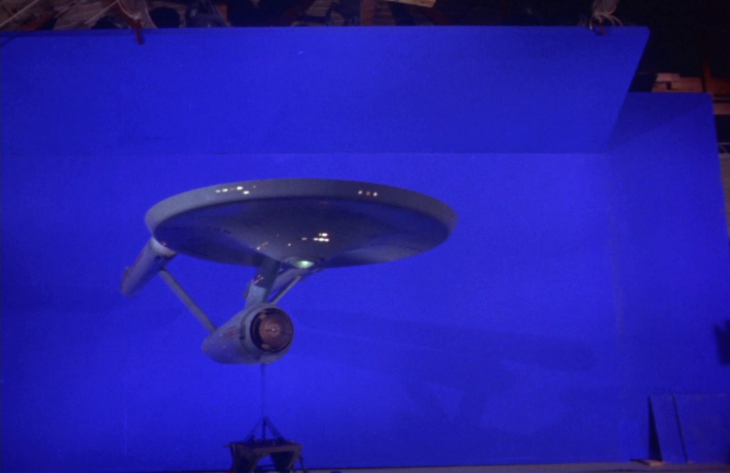 Behind-the-scenes photo/still frame from Star Trek: TOS showing the original USS Enterprise model against a blue screen.