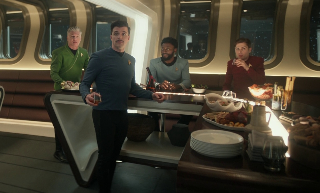 Still frame from Star Trek: Strange New Worlds 3x02 Wedding Bell Blues showing Pike, Kirk, M'Benga, and Scotty in Pike's cabin.