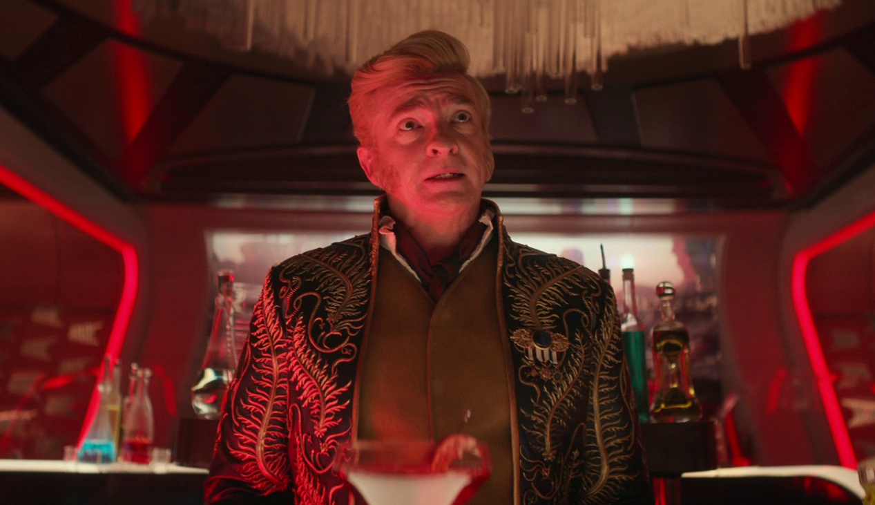 Still frame from Star Trek: Strange New Worlds 3x02 Wedding Bell Blues showing Trelane illuminated by red lights.