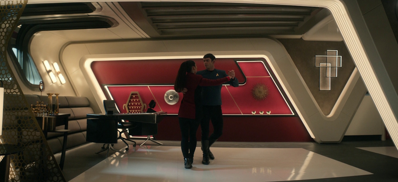Still frame from Star Trek: Strange New Worlds 3x04 "A Space Adventure Hour," showing La'an and Spock dancing.