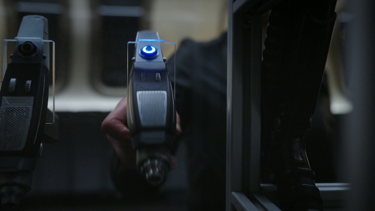 Still frame from Star Trek: Strange New Worlds S03E07 "What Is Starfleet?" showing a hand reaching for a phaser.