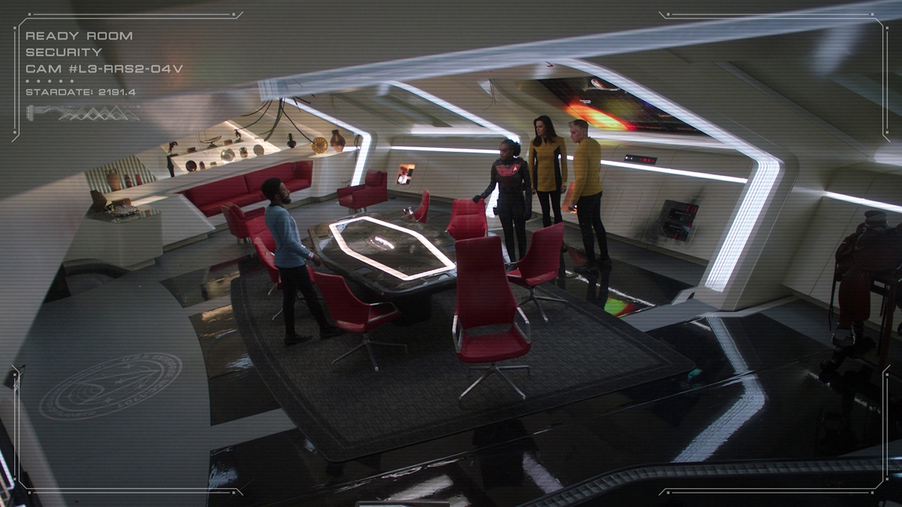 Still frame from Star Trek: Strange New Worlds S03E07 "What Is Starfleet?" showing Pike, Una, Uhura, and M'Benga in the ready room.