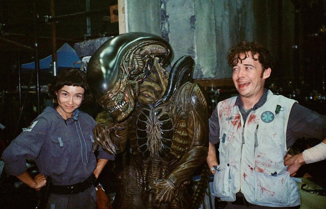 Behind-the-scenes photo from the set of Alien: Earth showing Sydney and Alex posing with the Xenomorph.