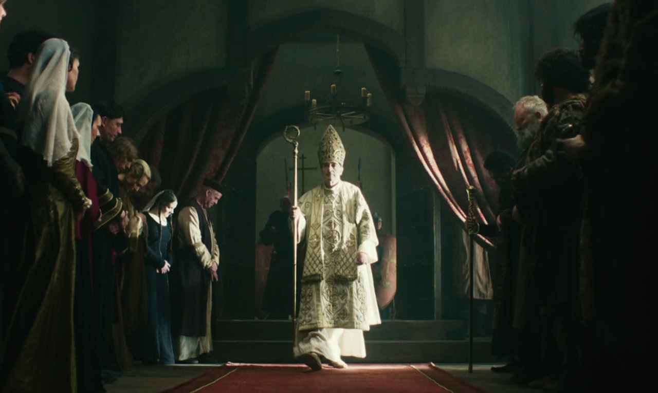 Still frame from King & Conqueror (2025) showing the bishop at the coronation.