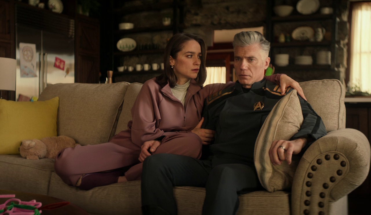 Still frame from Star Trek: Strange New Worlds 3x10 (New Life and New Civilizations) showing Batel and Pike on the couch in their fantasy life.