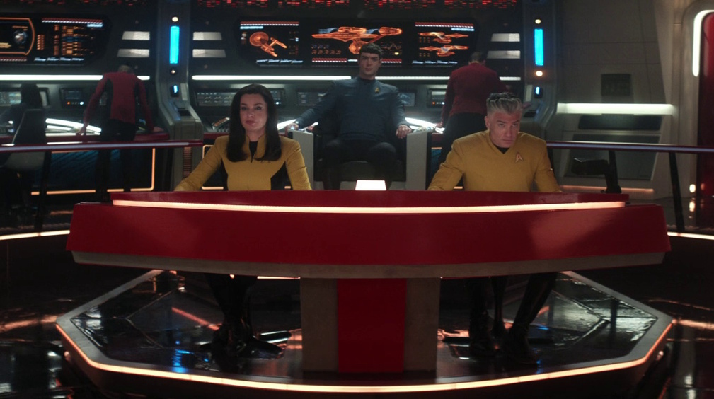 Still frame from Star Trek: Strange New Worlds 3x09: Terrarium, showing Spock in the captain's chair with Una and Pike at the helm/navigation console.