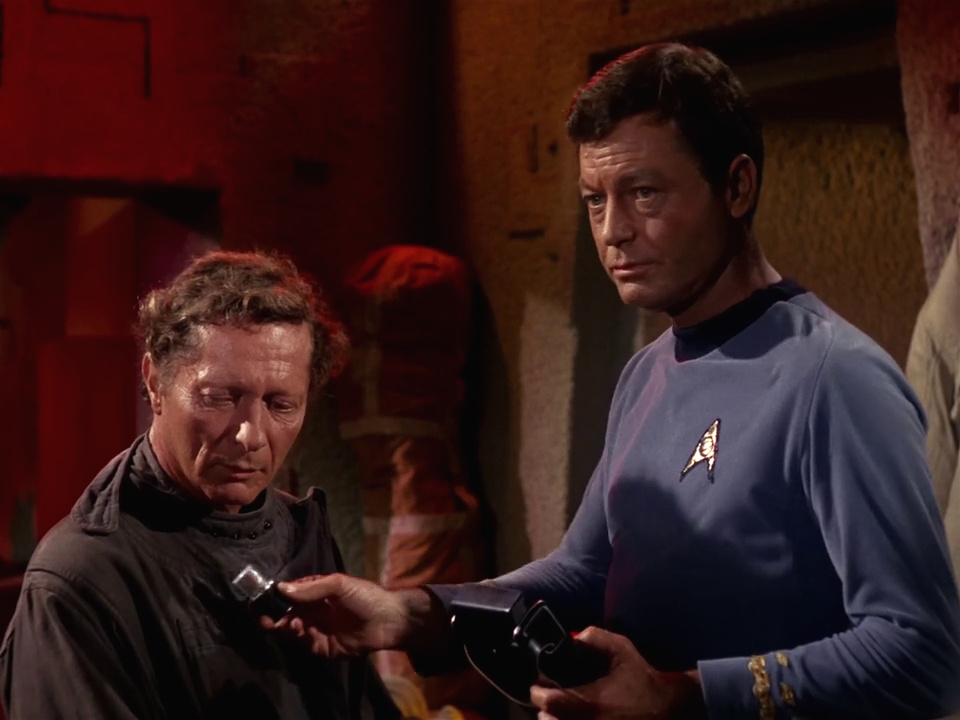 Still frame from Star Trek: The Original Series S01, E01, "The Man Trap," showing Dr McCoy holding his medical tricorder.