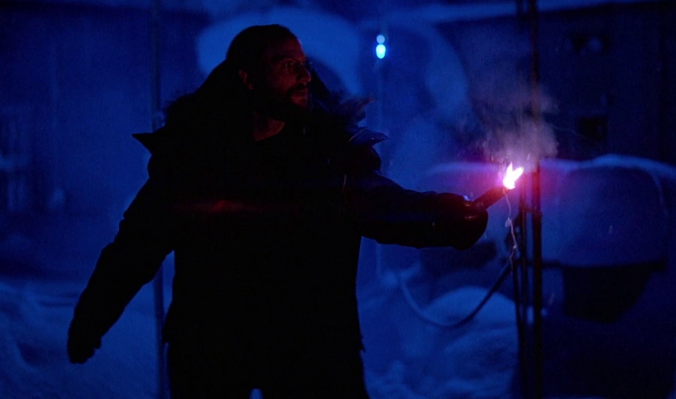 Still frame from The Thing showing a character holding a lit flare.