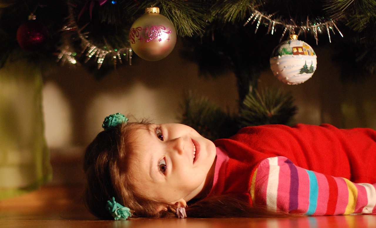 Stock photo of a little girl lying down under a Christmas tree.