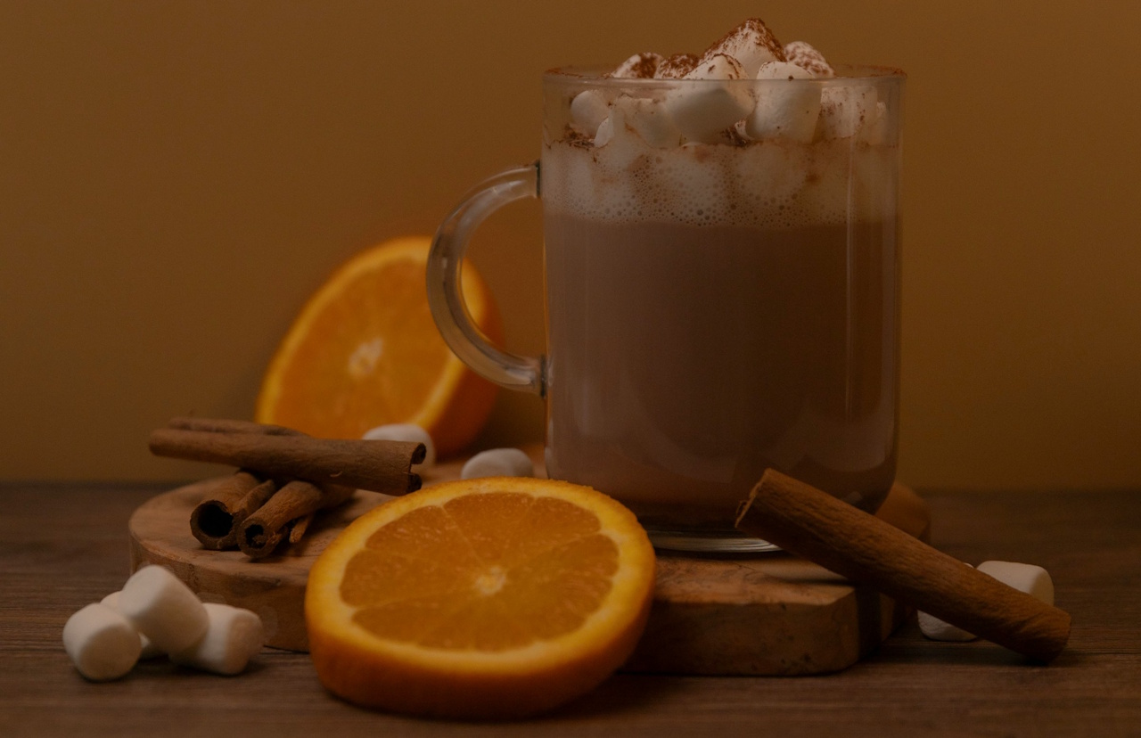 A stock photo of a glass mug of hot chocolate/hot cocoa with marshmallows and orange slices.
