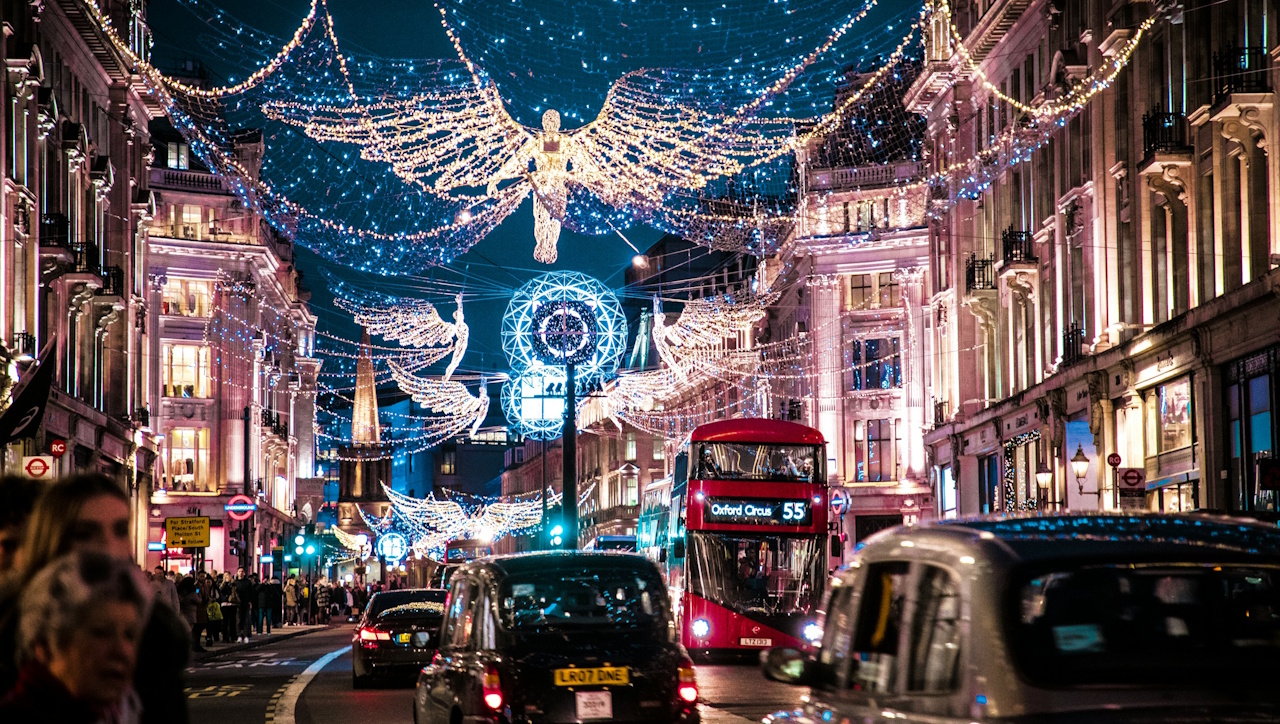 A stock photo of a London street with Christmas lights, a Routemaster bus, and a black cab.