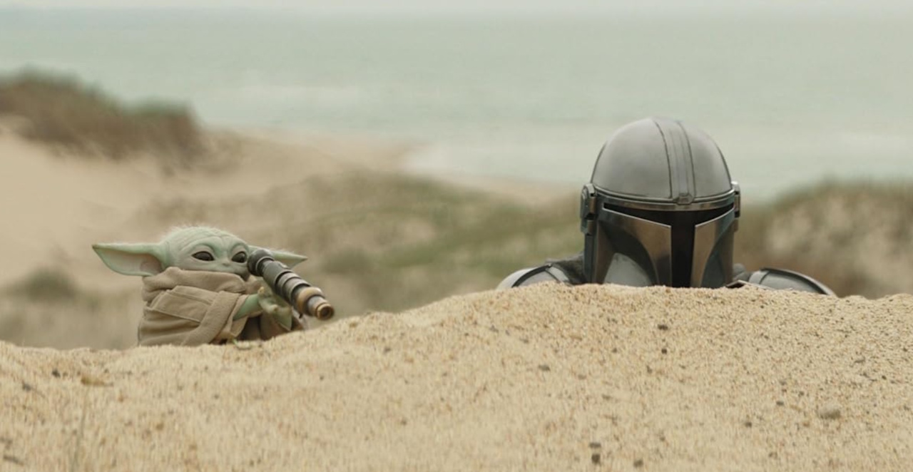 Promo image (cropped) for The Mandalorian and Grogu showing the title characters on a sand dune.