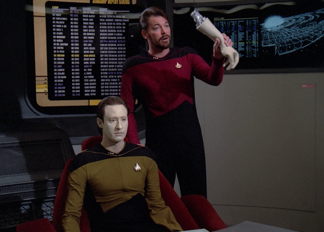 Still frame from Star Trek: The Next Generation (The Measure of a Man) showing Riker holding Data's arm at the trial.