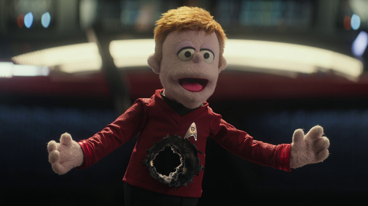 Still frame from Star Trek SNW 4x05 showing the puppet navigator with a hole shot through him