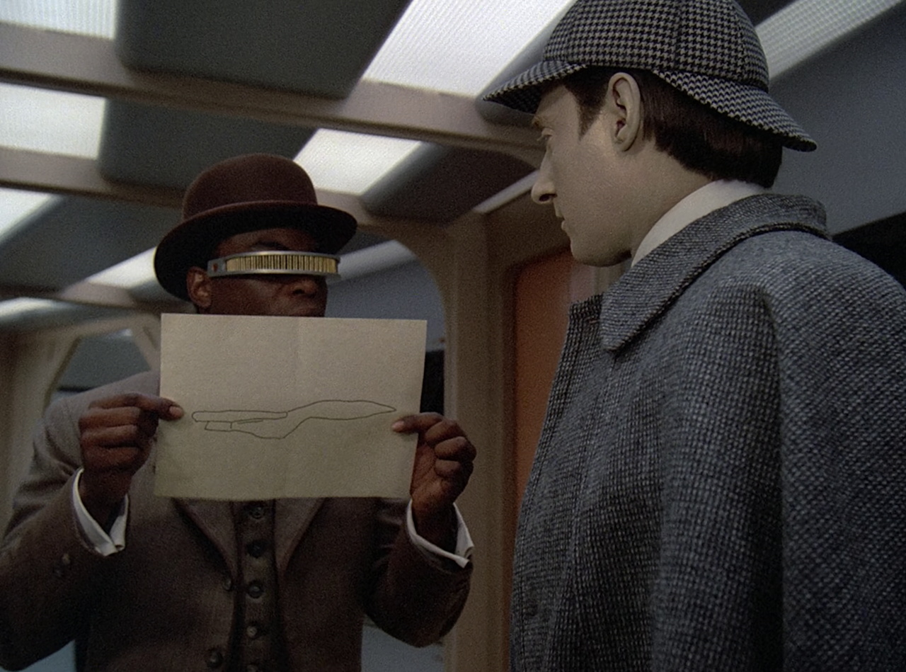 Still frame from Star Trek TNG 2x03 showing Data, Geordi, and a drawing of the ship